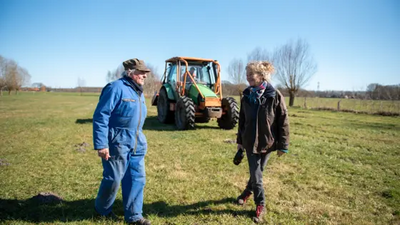 Mevrouw Schutman met buurman op het land, tractor achter hen