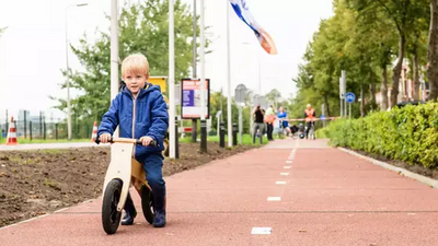 Kind op loopfietsje op het plastic road fietspad