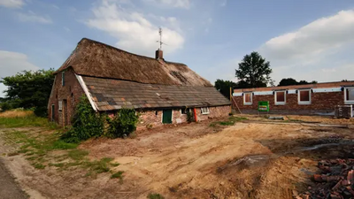 oude boerderij met daarachter een huis in aanbouw