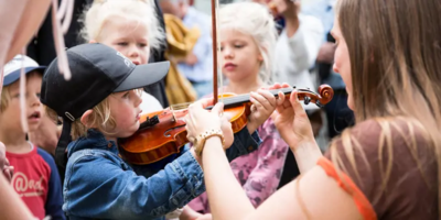 kind met een viool, volwassene geeft de vioolstok aan
