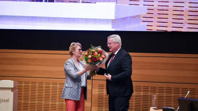 Carla Evers biedt Andries Heidema een bos bloemen ter felicitatie aan