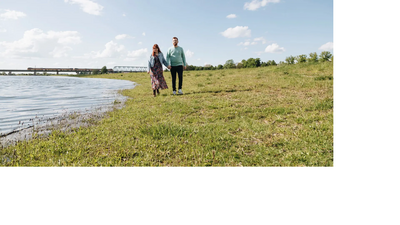 2 personen lopen aan de oever van een rivier